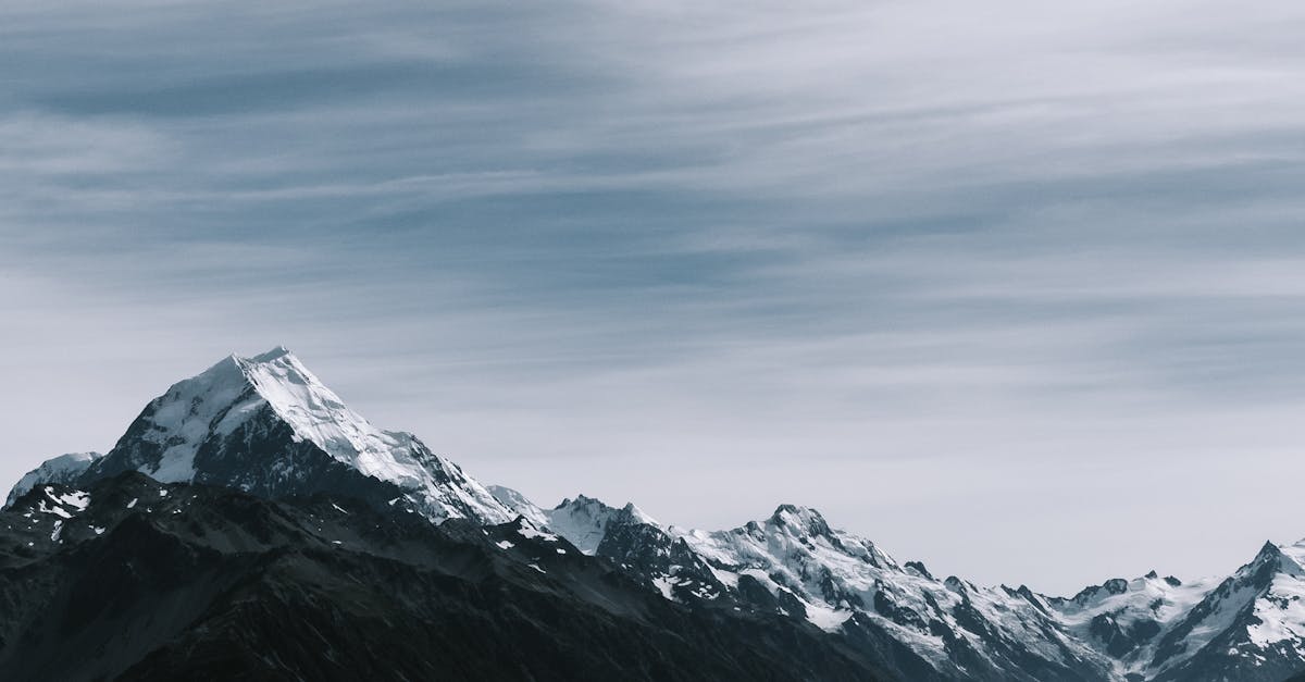 Breathtaking view of snow-capped mountain peaks under a cloudy sky.